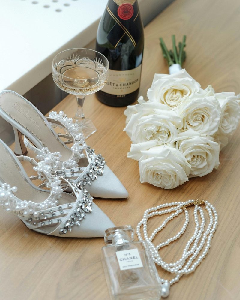 Wedding shoes, pearls, a tiara and white roses on a table
