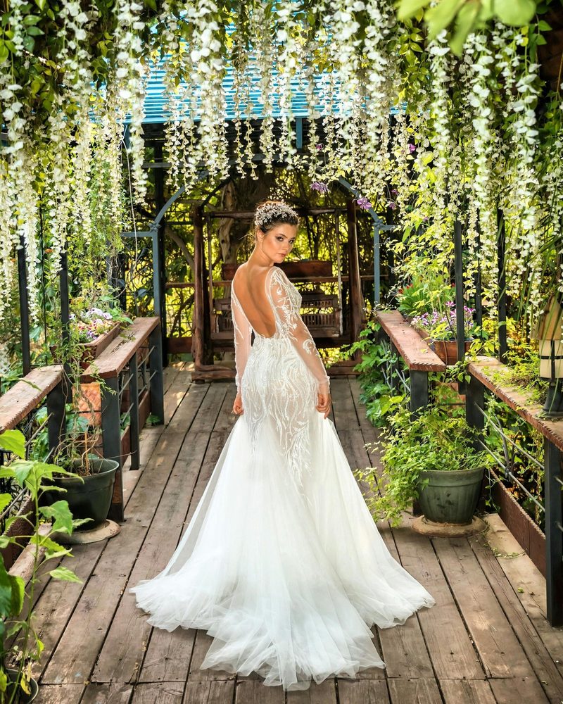 A woman in a long gown walking through a garden walkway