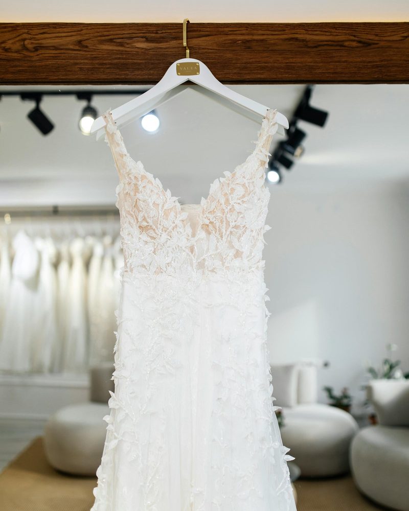 A lace wedding gown on a wooden hanger