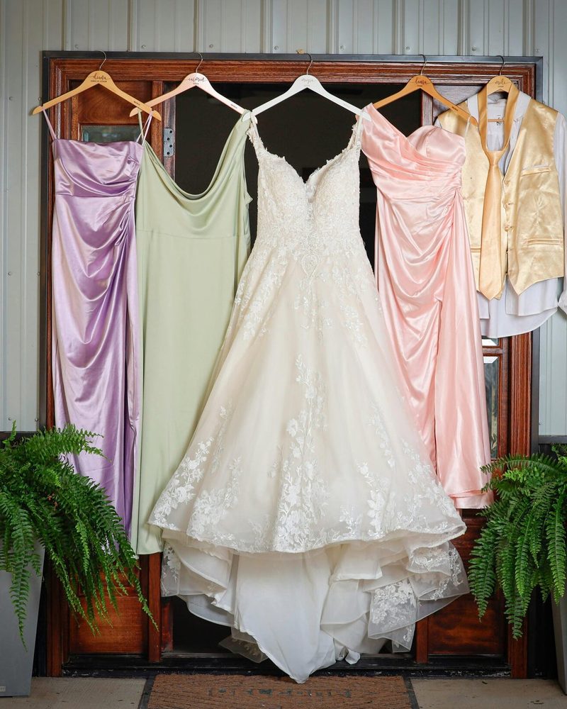 Bridesmaid dresses in lilac, sage and blush beside a wedding gown