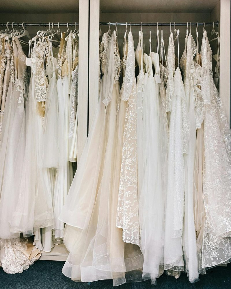 A rail of ivory wedding gowns in a bright boutique